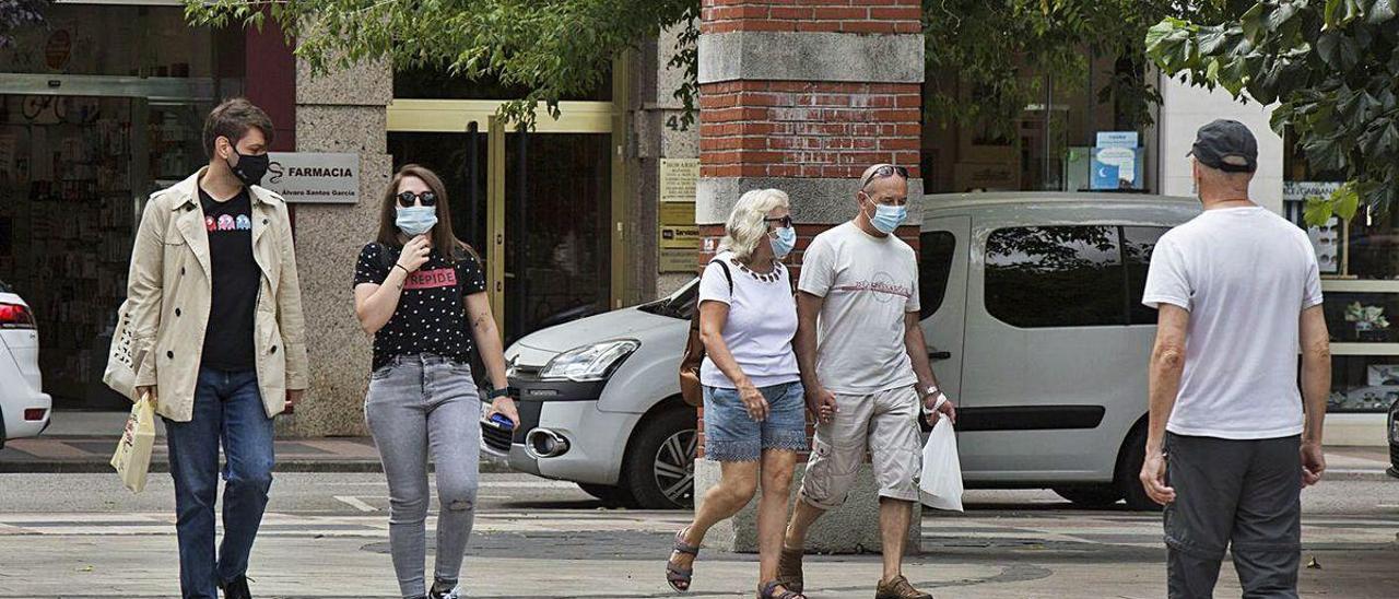 Vecinos de Mieres paseando por la calle con mascarilla.