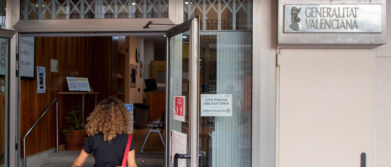 Una ciudadana accede a la oficina del PROP de la calle Mayor de Castelló, donde figura el cartel de &quot;cita previa obligatoria&quot;