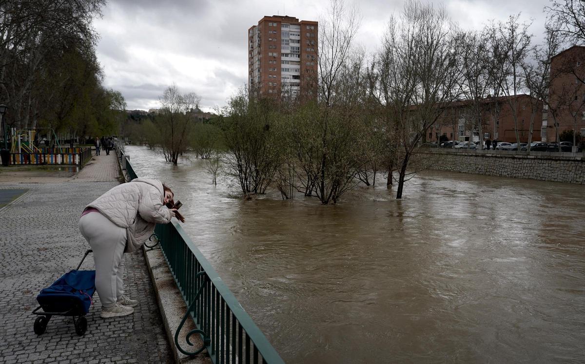 Una mujer fotografía el río Manzanares este viernes tras su paso por el Puente de los franceses