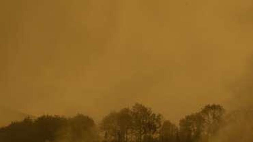 Una zona de Ibias, al mediodía, cubierta por el humo.