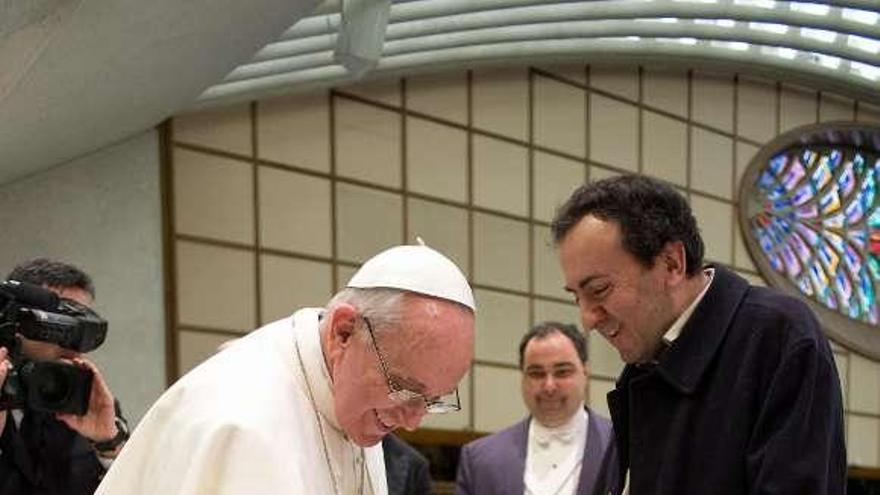 El Papa acaricia al perro lazarillo de un periodista.  // Reuters