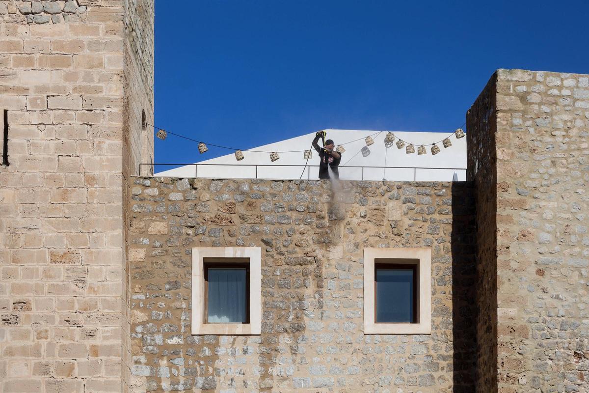Un hombre limpia la fachada del Parador de Ibiza