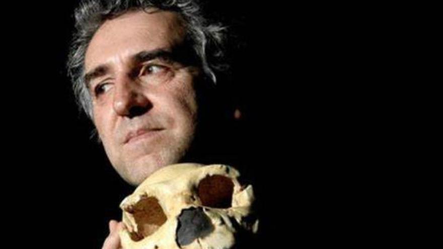 El paleoantropólogo Juan Luis Arsuaga sosteniendo entre sus manos el cráneo de un homínido.