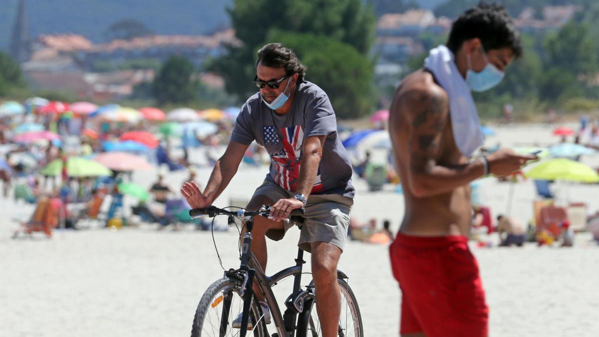 Gente con mascarillas en el entorno de la playa de Ladeira, en Baiona. // M.G. Brea