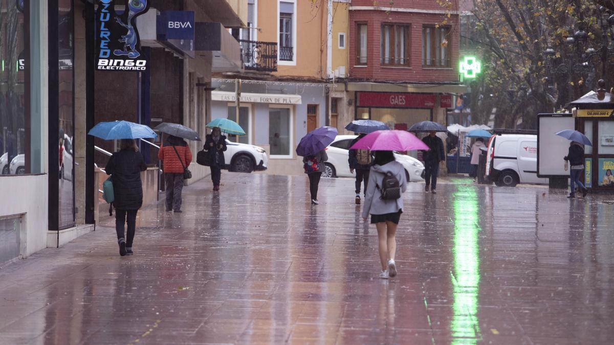 Un grupo de personas pasea por la Alameda de Xàtiva bajo la persistente lluvia.