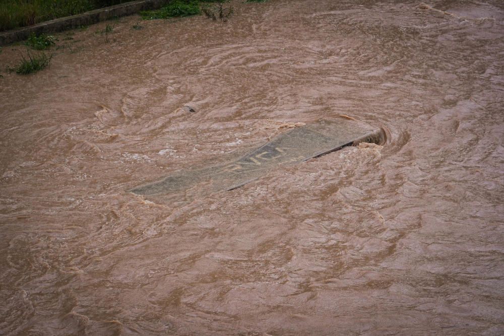 El río Guadalmedina crecido con agua y calles del Centro y el entorno del cauce, desiertas bajo la lluvia, la estampa de este martes 31 de marzo.