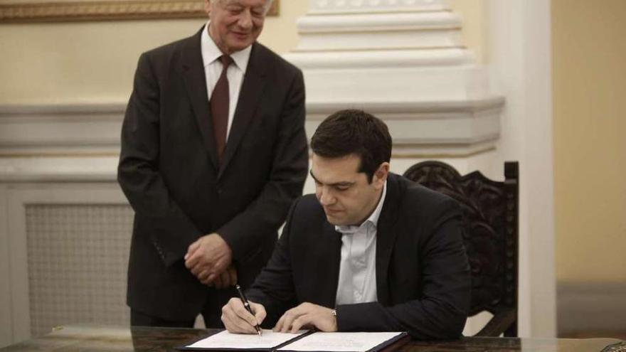 Alexis Tsipras firma su primer documento tras tomar posesión como primer ministro griego. // Efe