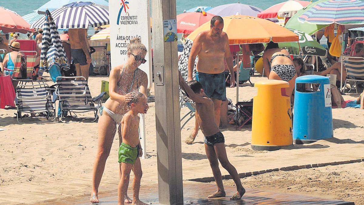 Una familia utiliza una de las ducha de la playa de la Concha de Orpesa.