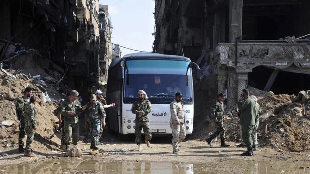 Militares del Ejército sirio supervisan un autobús que transporta combatientes vinculados a Al Qaeda durante una evacuación desde el campo de refugiados palestinos de Yarmuk, cerca de Damasco.