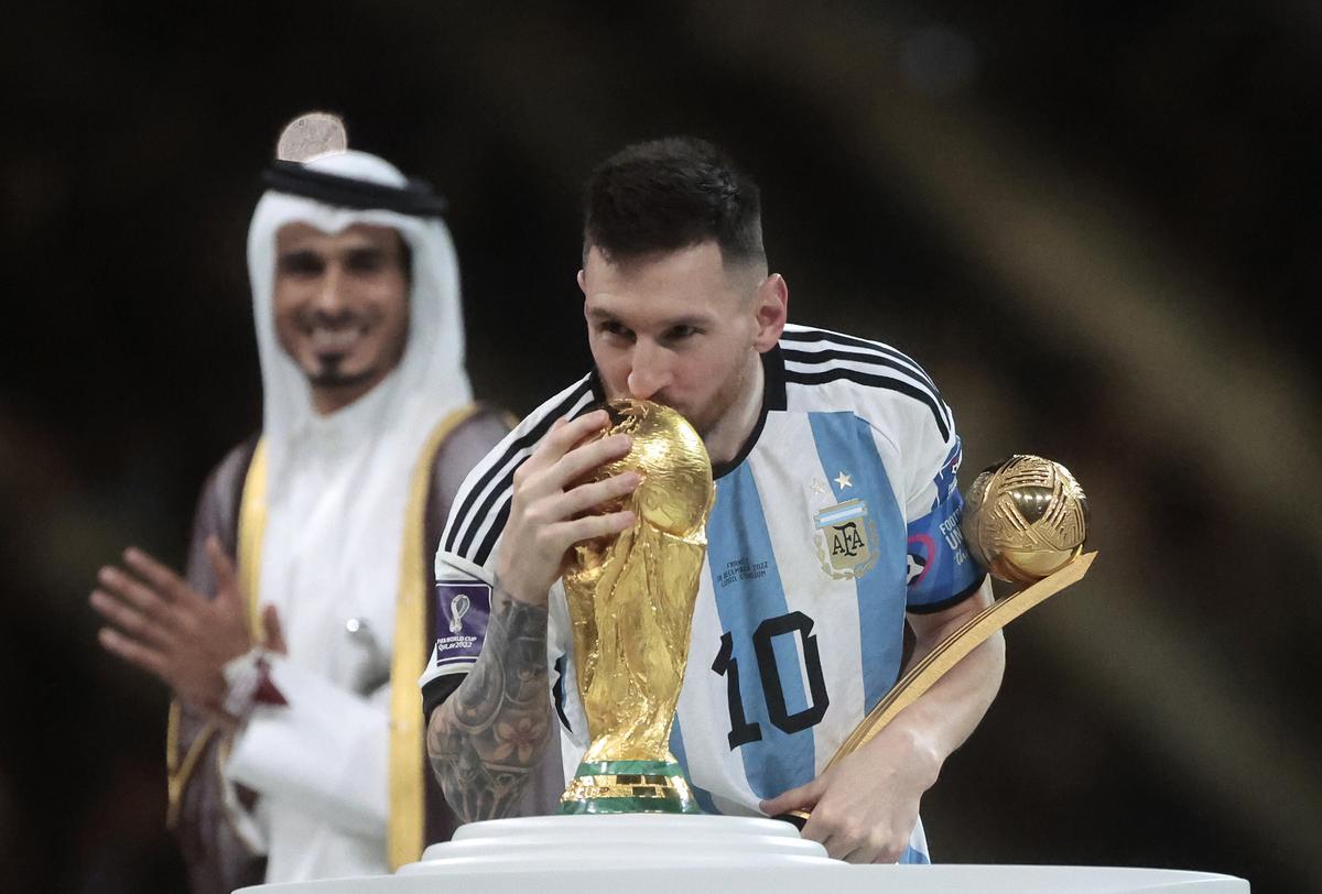 Messi besa la Copa del Mundo con el trofeo de Mejor jugador del Mundial de Fútbol 2022 en la otra mano.