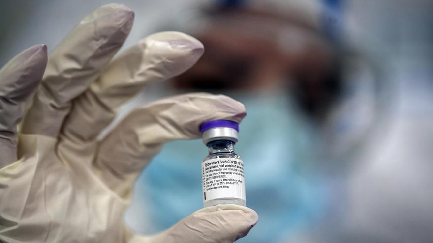 Un sanitario sostiene un vial de la vacuna de Pfizer y Biontech