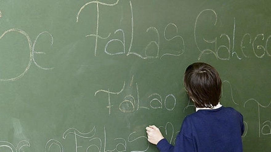 Un alumno escribe en lingua galega na pizarra da súa clase.