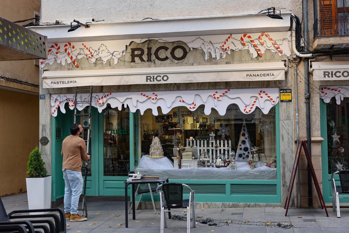 El encargado de un comercio de la Plaça de la Palla instalando adornos navideños, algo por lo que han optado bastantes establecimientos.