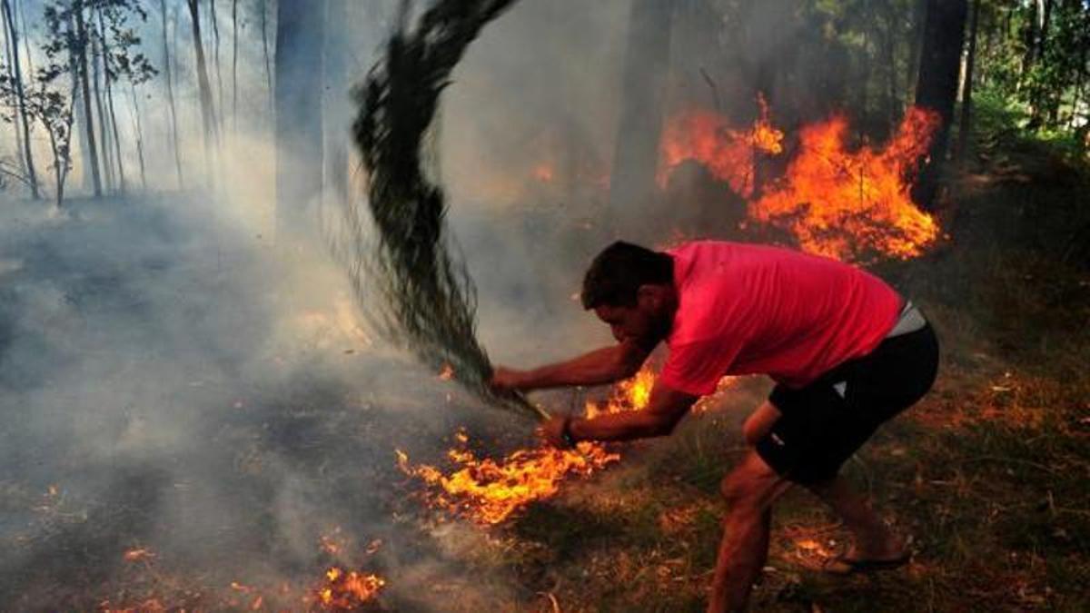 Un hombre trata de contener el avance de las llamas de un incendio.