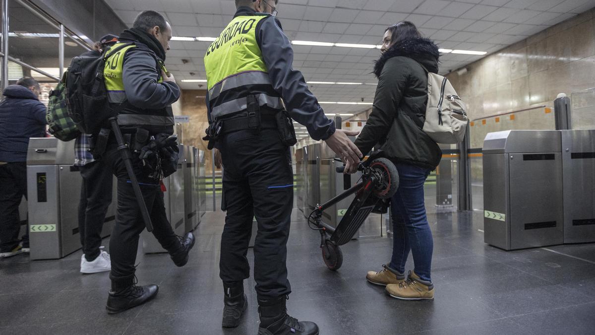 Usuaria del metro intentando entrar con su patinete eléctrico