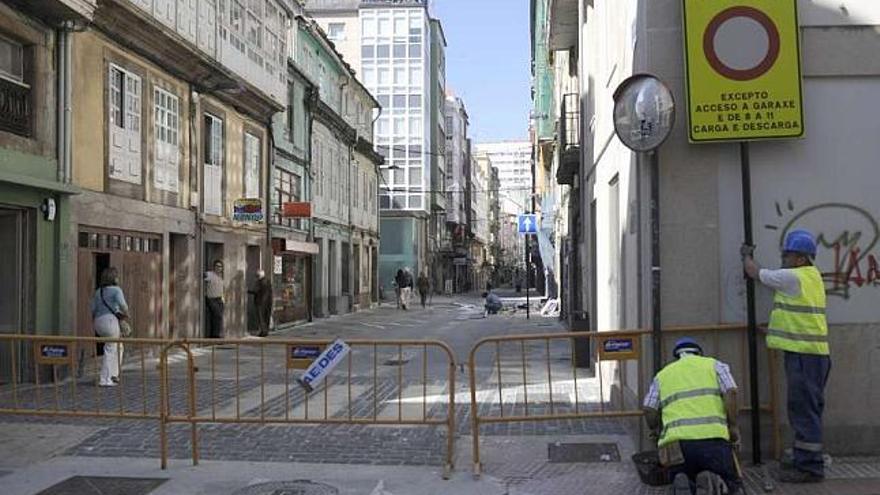 Dos operarios instalan ayer la señal que prohíbe la circulación de vehículos en el Orzán. / carlos pardellas