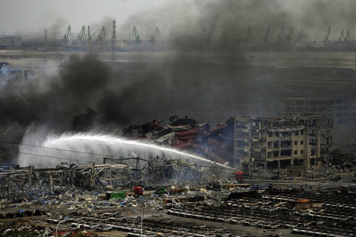 Els bombers remullen la zona de les explosions de Tianjin, aquest divendres.