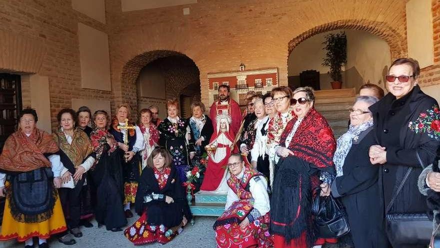 Las mujeres participantes posan con el párroco de la localidad junto a la imagen de Santa Águeda.