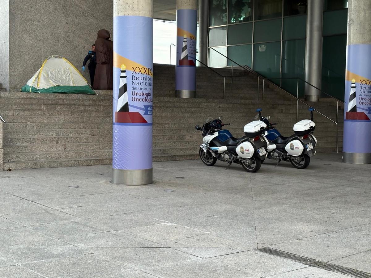 Un policía local atiende a una persona sin hogar que pernocta en el acceso al auditorio Mar de Vigo.