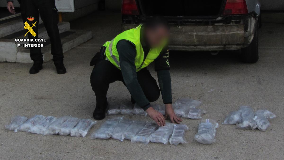 Un agente inspecciona los paquetes de droga hallados en el parachoques