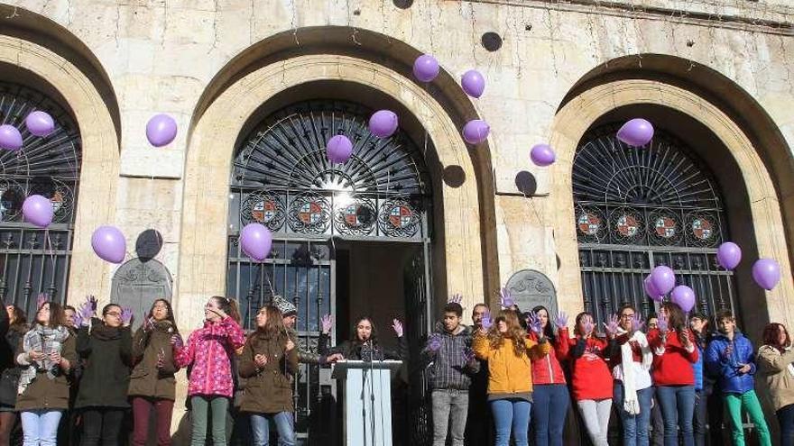 Jóvenes palentinos, con globos morados en recuerdo de las víctimas de la violencia de género. A la derecha, &quot;performance&quot; realizada en Soria.