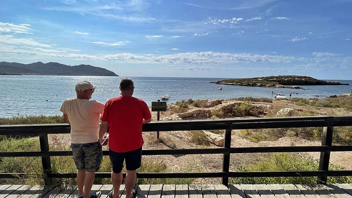 Unos viandantes visitan los yacimientos de los Baños Termales de Isla Plana y Los Tinteros (izq.) y su edificio termal (dcha.). | A. C.