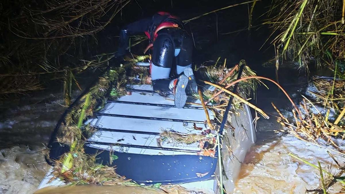 Un efectiu dels Bombers sobre el sostre d'una furgoneta arrossegada per la riera Nova a Palau-sator.