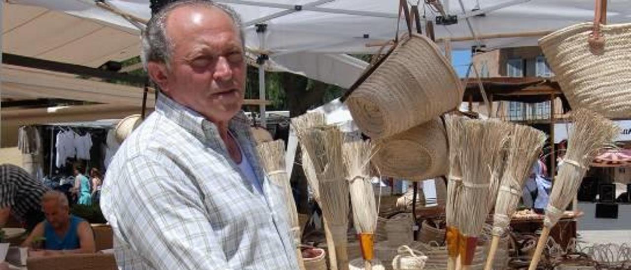 ´Mestre´ Pep Cerdà muestra una de sus escobas tradicionales su puesto de venta de una feria .