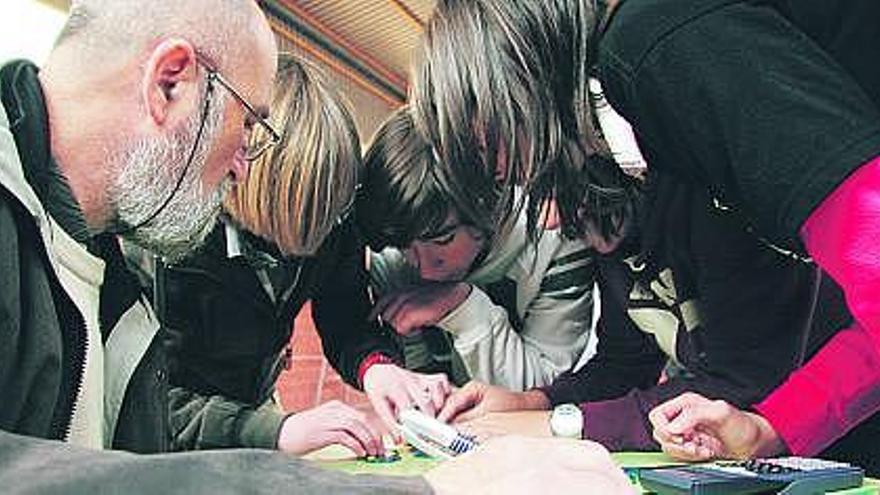 Arriba, varios de los grupos en que se dividieron los participantes, ayer, en el polideportivo del IES Ramón Areces de Grado. A la izquierda, los alumnos resuelven uno de los problemas.