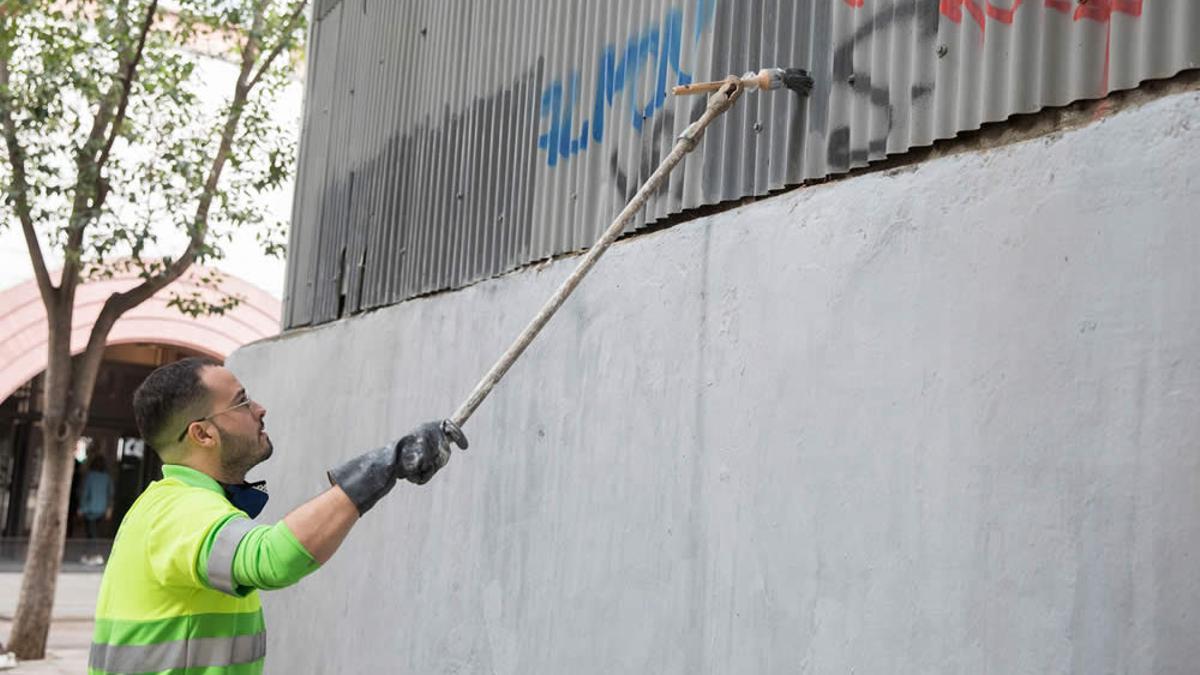Un empleado del servicio de limpieza borra una pintada.