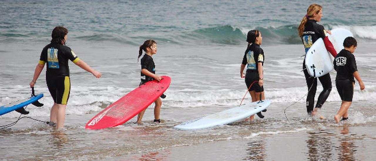 Un grupo de menores en un curso de surf en la playa de Las Canteras. Se estima que el nivel del mar crecerá unos tres metros en 2040.