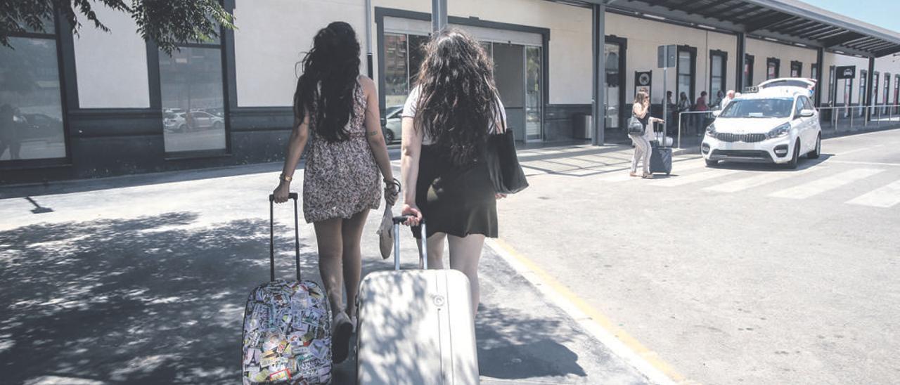 Dos chicas con sus maletas, dirigéndose a la estación de tren.