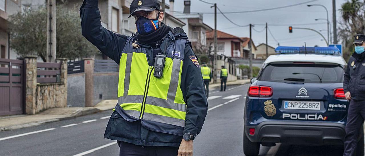 Un policía levanta la mano para ordenar la detención de un vehículo en Ourense.   | // B. LORENZO