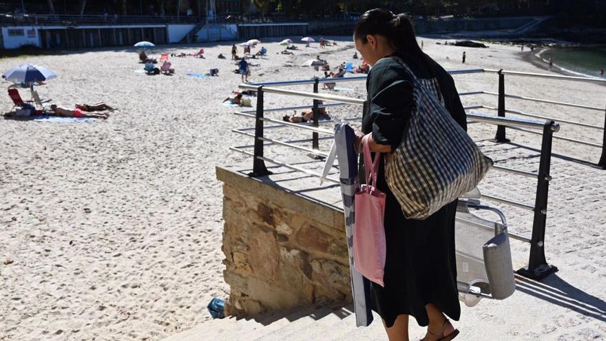 Una mujer se dirige, con su sombrilla y su silla, a la playa de Portocelo, ayer