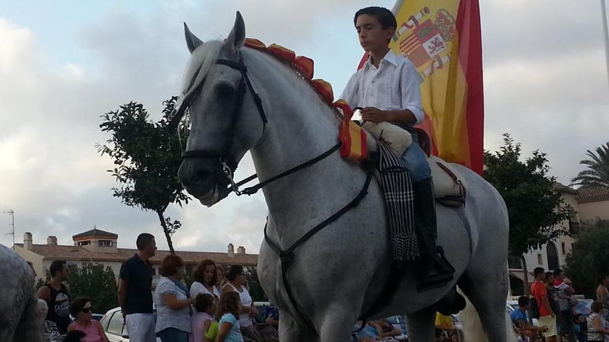 Un niño posa a caballo con una bandera de España.