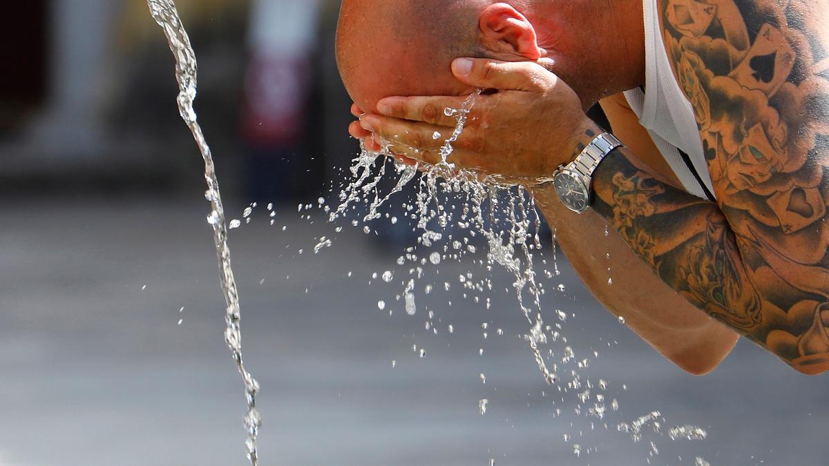 Un hombre se echa agua en la cara para soportar las altas temperaturas.