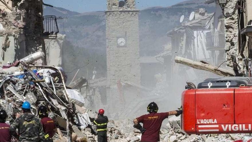 Bomberos observan la demolición de casas en ruinas. // Efe