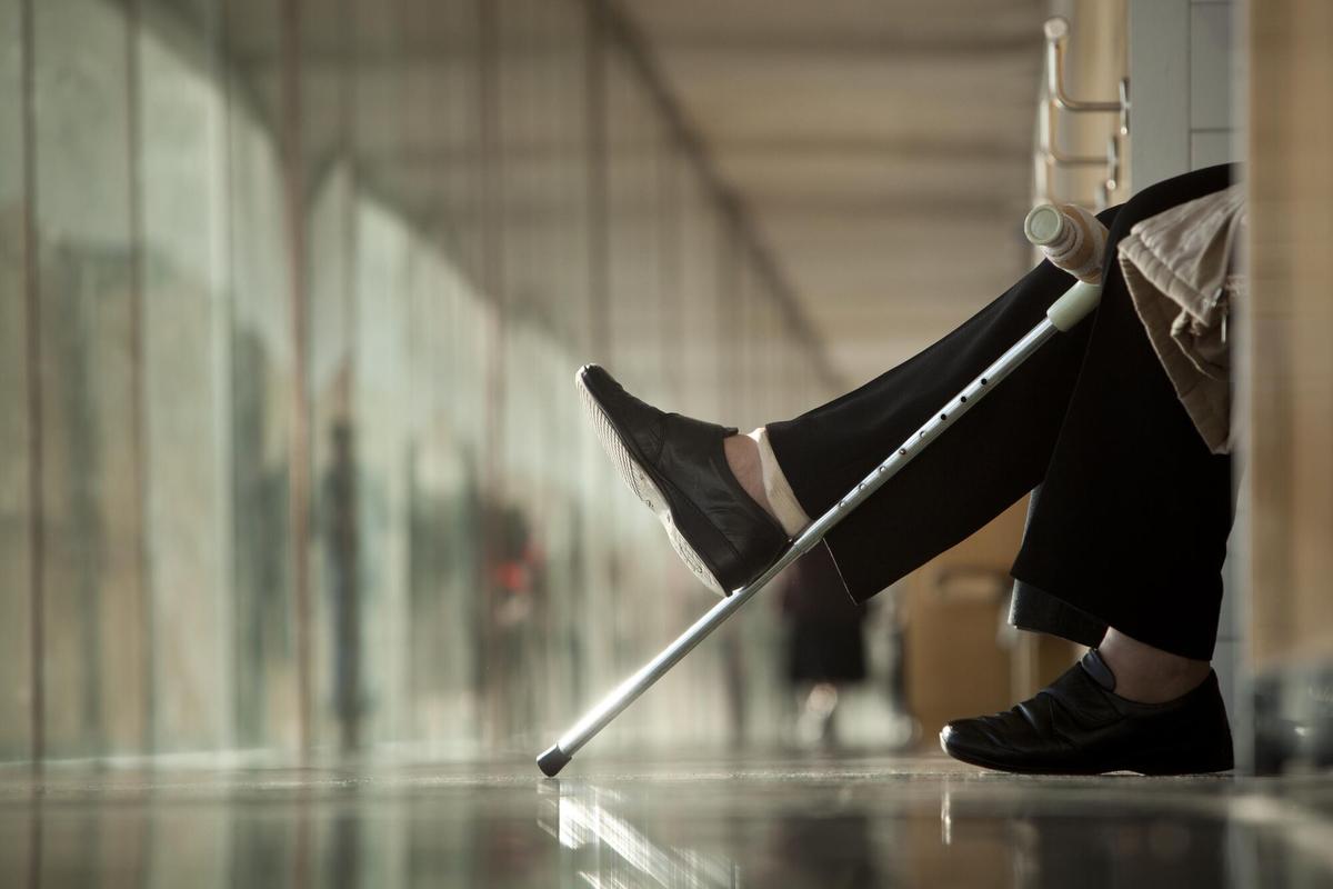 Imagen de archivo de una persona de baja laboral con muletas en la sala de espera de un centro de salud.