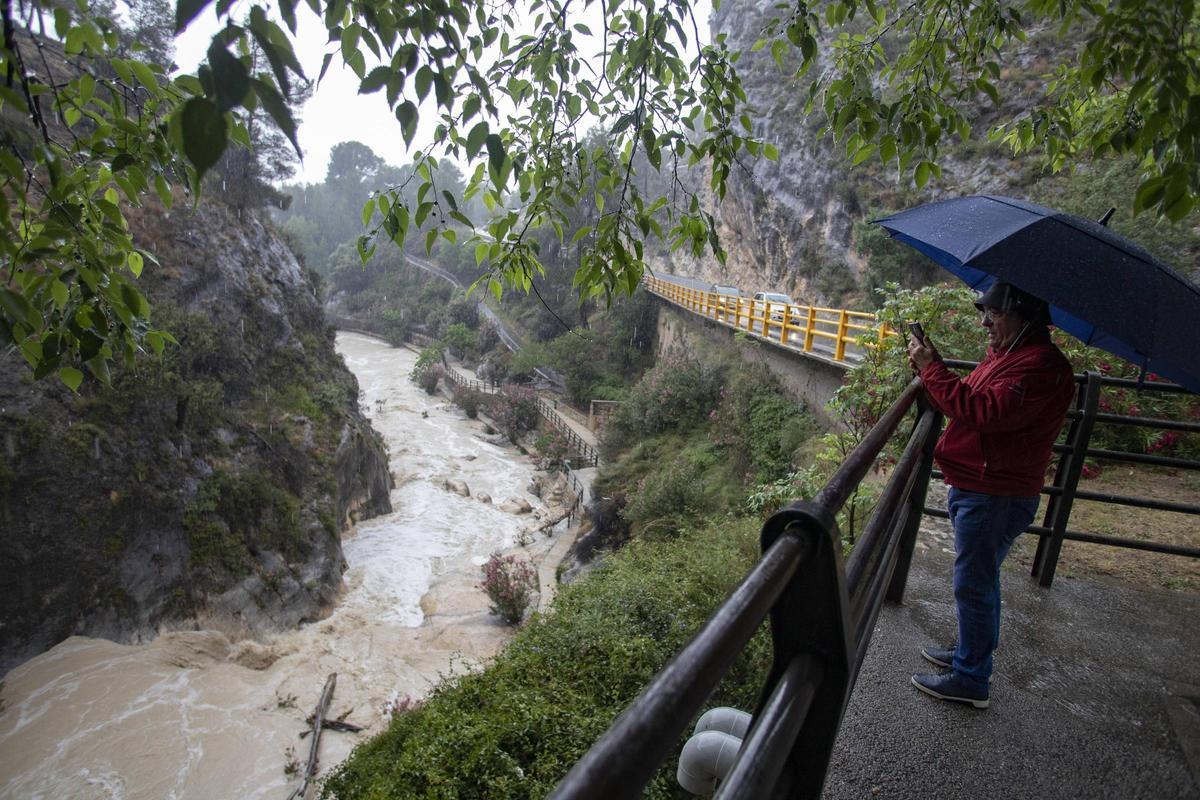 Un curioso obsesrva la crecida del río Clariano en el Pou Clar de Ontinyent.