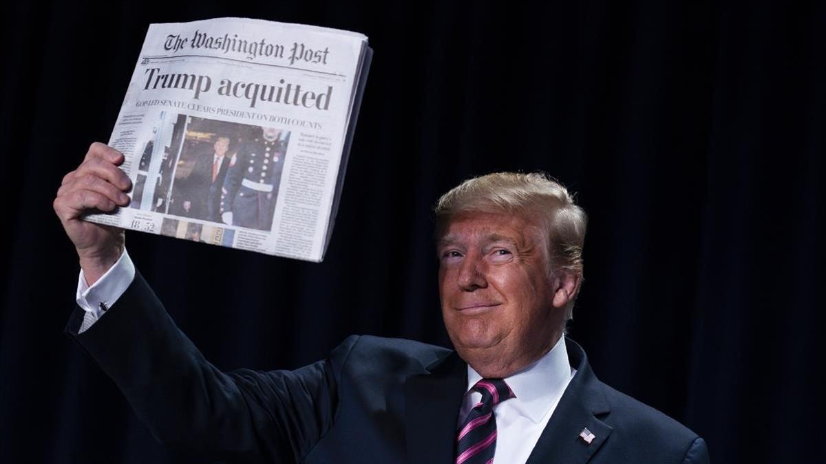 Donald Trump muestra un ejemplar de periódico.