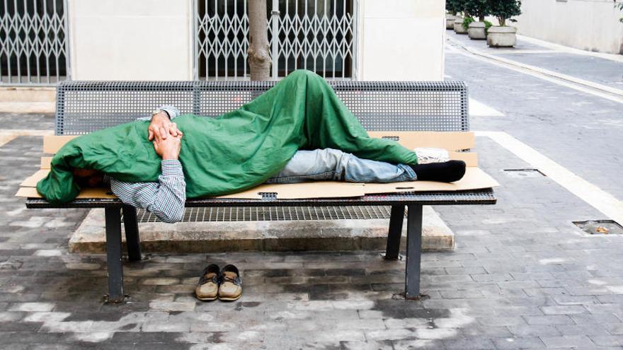 Un hombre &#039;sin techo&#039; descansa en un banco.