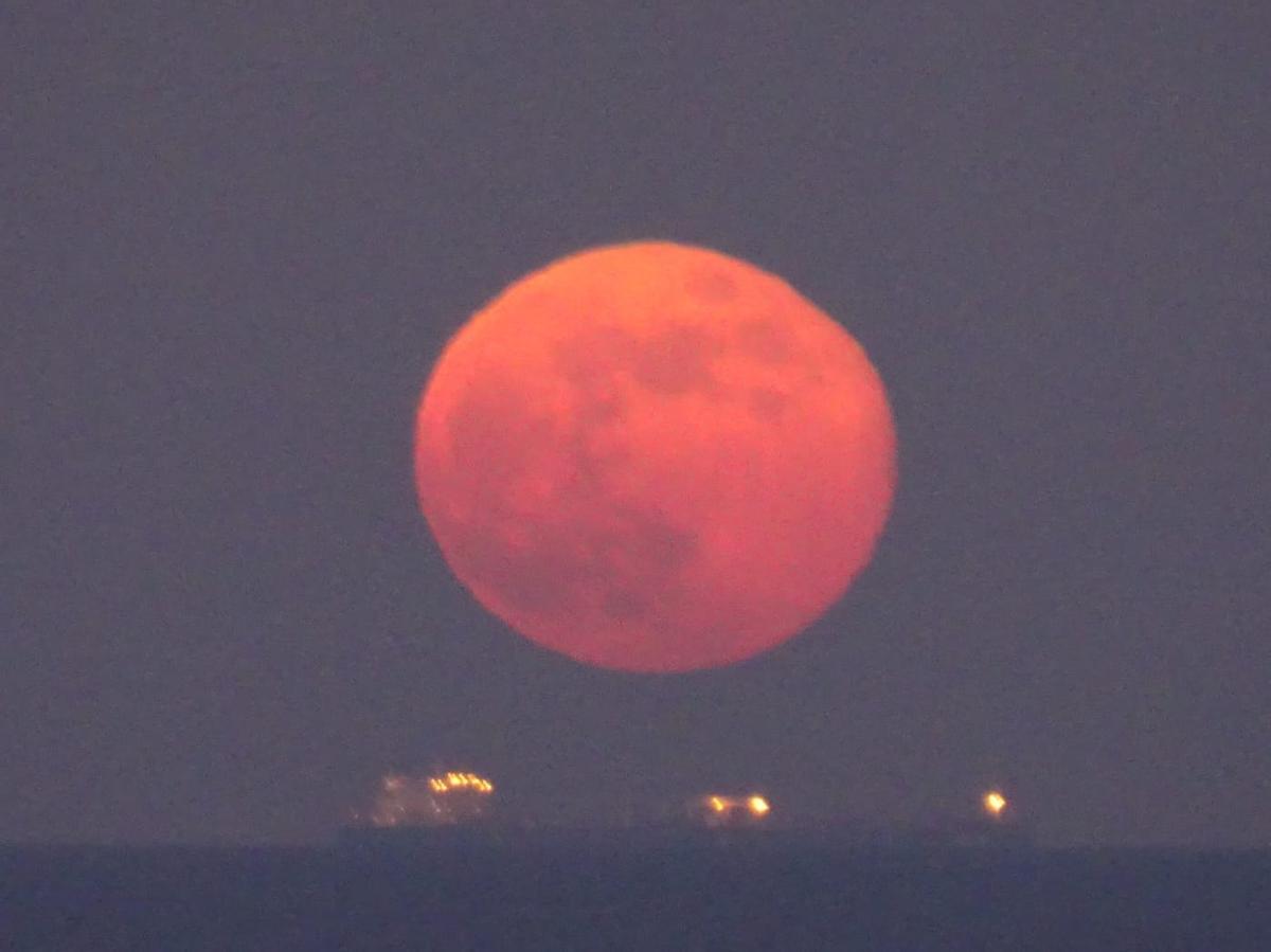 Espectacular imagen de la luna sobre los barcos en el horizonte.
