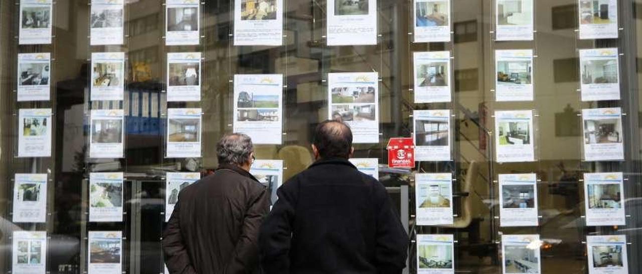 Dos hombres, obsevando carteles de venta y alquiler de Inmuebles en Vigo. // Alba Villar