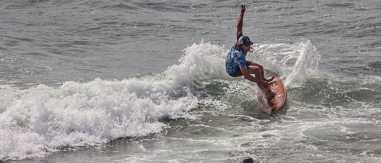 Un surfista toma una ola en la playa de Cala Cerrada, en Orihuela Costa, donde se permite el surf en temporada baja durante todo el día.