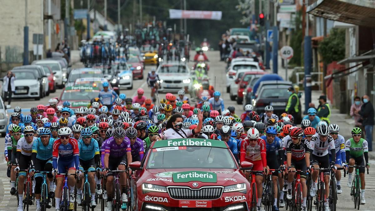 Nidia Arévalo saluda a sus vecinos desde el coche de carrera que encabeza el pelotón de ciclistas, en la salida de etapa desde Mos.