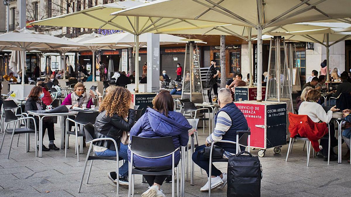 Varios grupos de personas toman algo en una terraza.