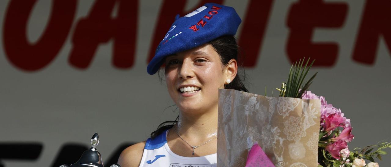 Arriba, Isabel Barreiro en el podio con el trofeo, la chapela y el ramo. A la izquierda, con Cavaline Nahimana y Cristina  Espejo. A la derecha, marcando de cerca  a Nahimana durante  la carrera. | |  EFE