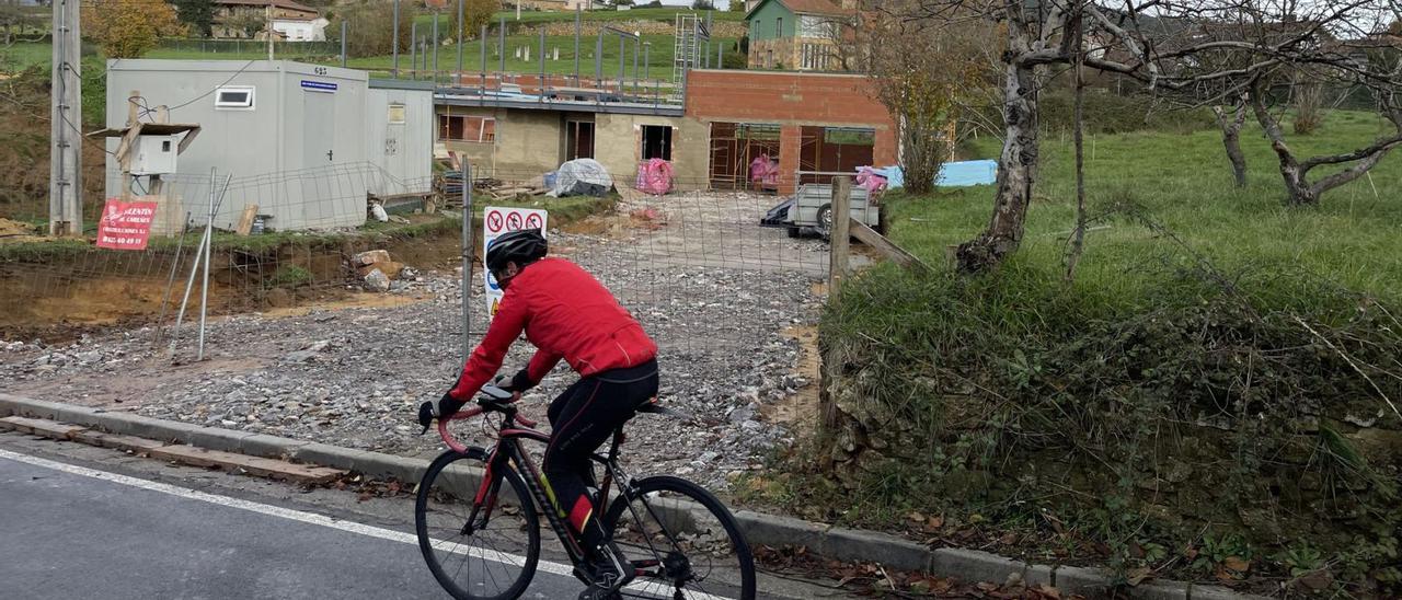 Un ciclista pasa ante una vivienda actualmente en construcción en San Cucao (Llanera). | |  LNE