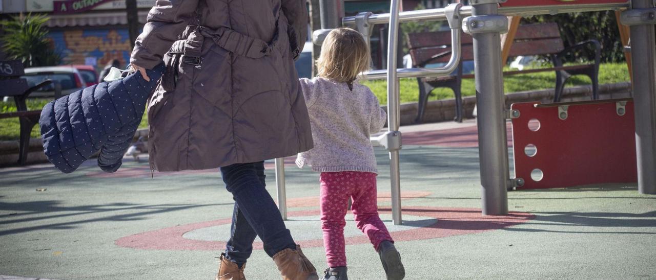 Una mujer pasea con una niña por un parque de Alicante.