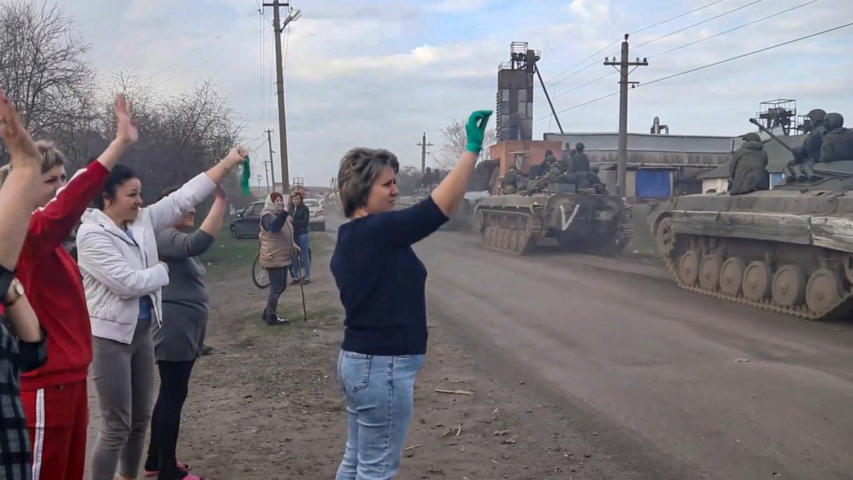 Varias personas saludan a los soldados rusos a su paso por la región de Járkov.
